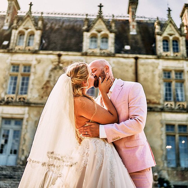 Les jeunes mariés s’embrassent devant le château